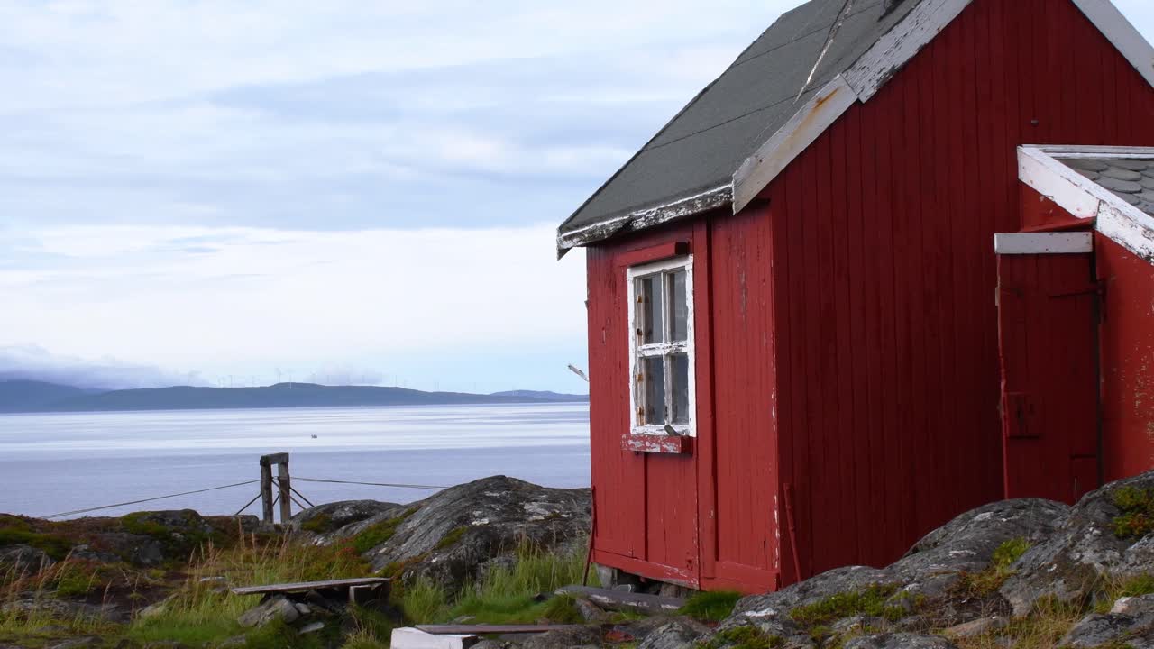 Pequeña cabaña de madera tradicional noruega pintada de rojo en la playa rocosa