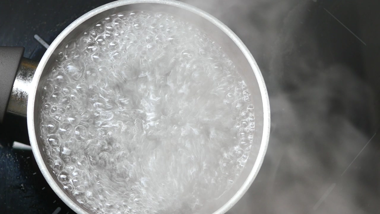 Primo piano di acqua che bolle e fuma in una pentola