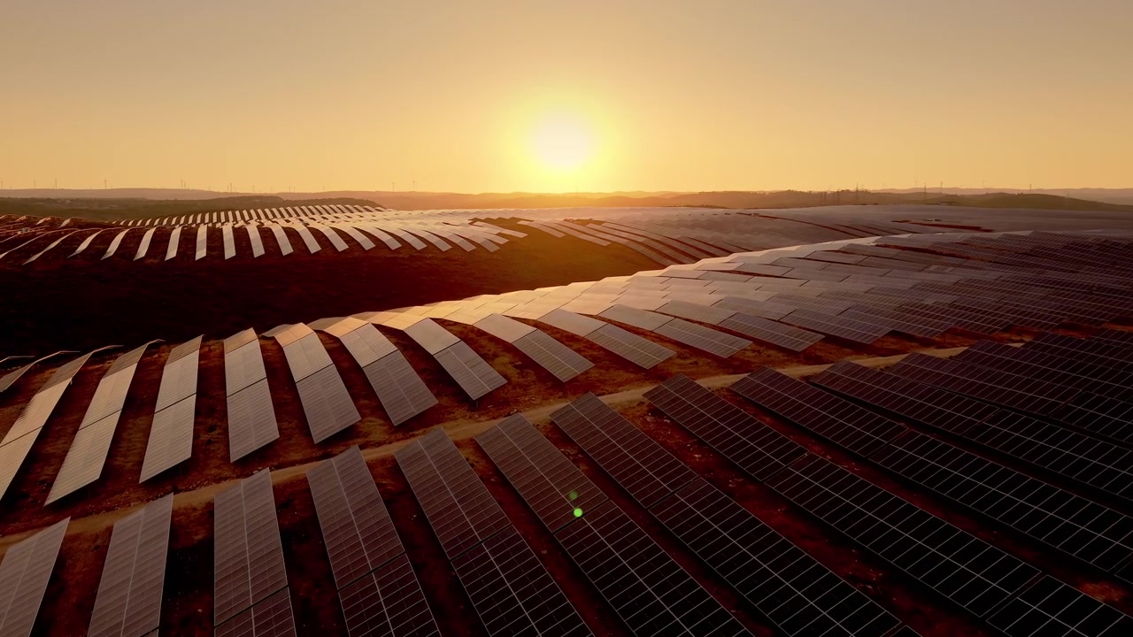 Luftfoto af stor solcellepark ved solnedgang