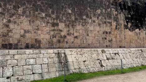 handheld wide tilting up shot of the stone ring on the court wall at the great mayan ball court in chichen itza, mexico. 4k