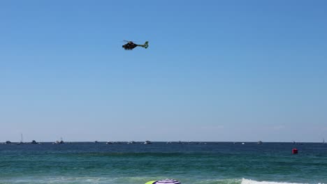 helicóptero volando sobre el océano con barcos y pájaros