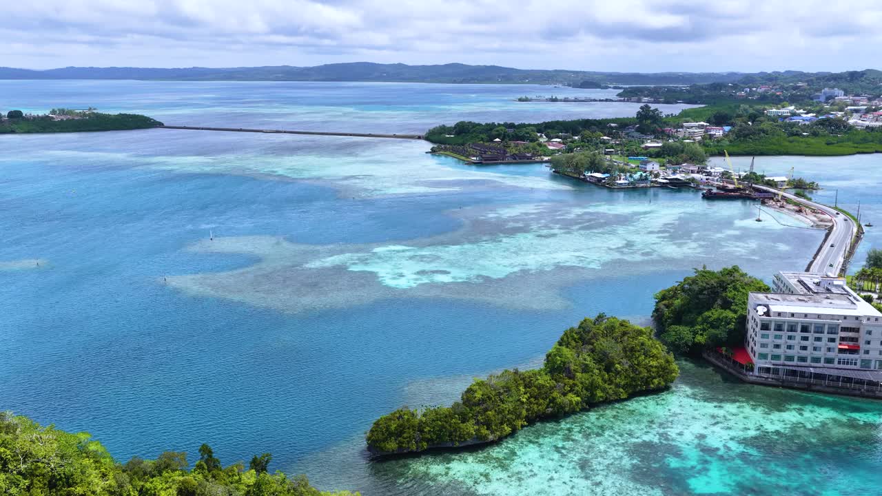 Riprese con drone catturano acqua turchese, barriere coralline e un hotel costiero in pieno giorno.