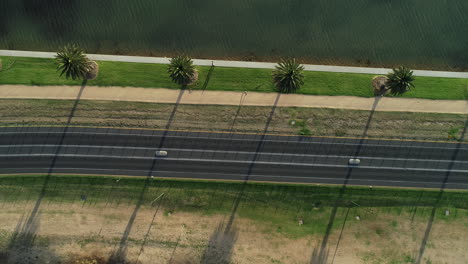 Menschen,-Die-Entlang-Des-Sandwegs-Am-Albert-Park-Lake-Spazieren,-Während-Der-Radfahrer-Um-Die-Kurve-Zwischen-Den-Linien-Kommt