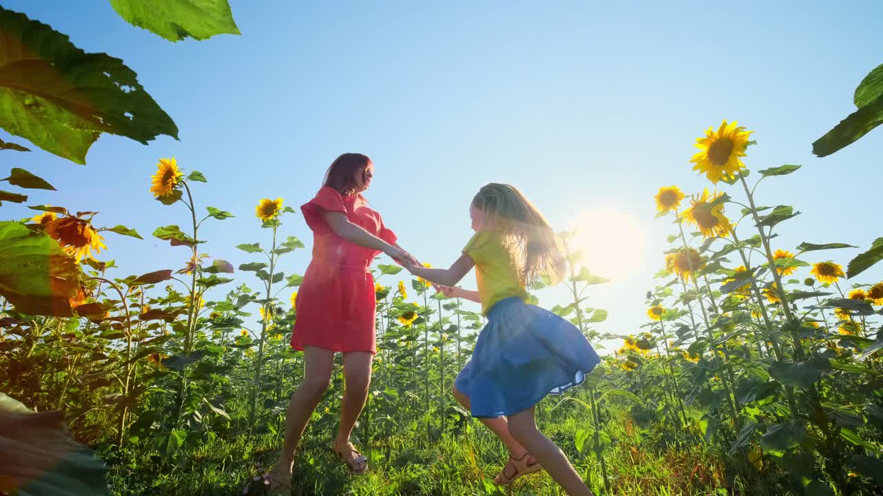 Madre e figlia che ballano in un campo di girasoli