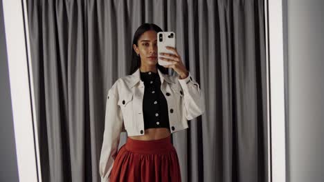 una mujer tomando una selfie en un camerino.