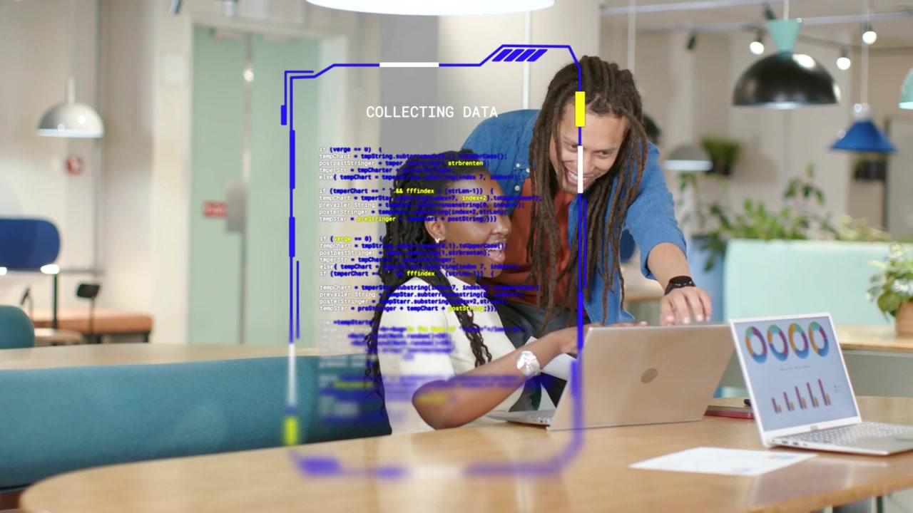 data overlay appearing over laptops while woman typing and man leaning pointing reviewing charts