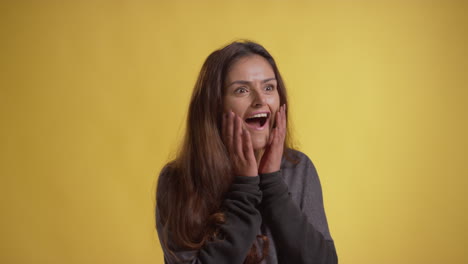 retrato de estudio de una mujer emocionada celebrando buenas noticias de pie contra un fondo amarillo 3