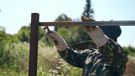 mature handyman taps with hummer on fixed fence details