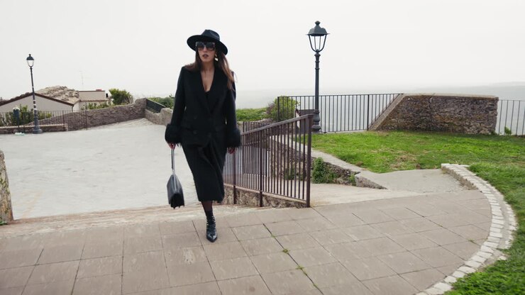 Modella elegante in total black che sfila nella piccola città italiana