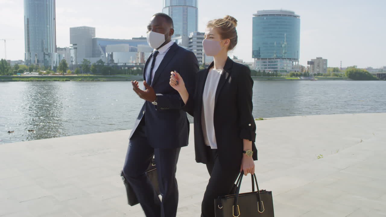 Business Couple In Masks Walking Along Embankment