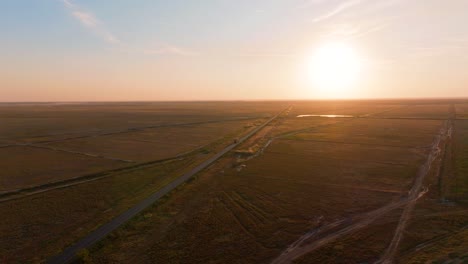 Aerial-tracking-shot-with-a-transport-truck-that-glides-along-a-straight,-sun-kissed-road