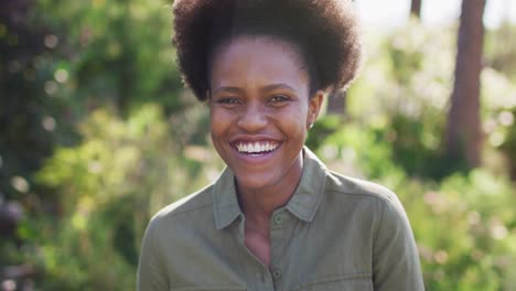 Portrait-of-smiling-african-american-woman-standing-in-sunny-garden