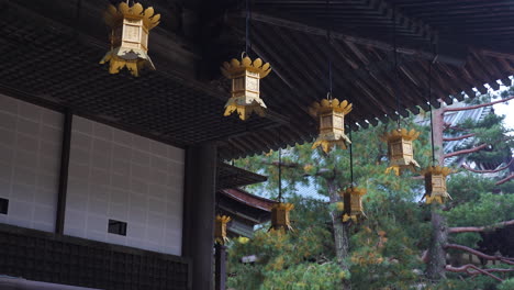 row of gold plated oriental lanterns hanging outside miedo hall japanese buddhist temple