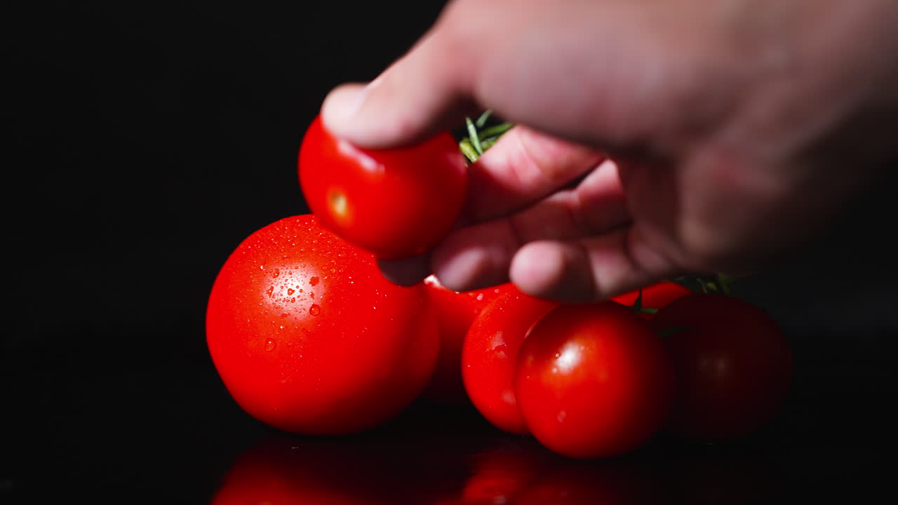 천천히 움직이는 토마토 더미에서 토마토를 뽑는 남성 손의 측면 시각