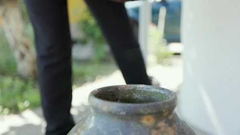 pouring water into an earthen jar - close up