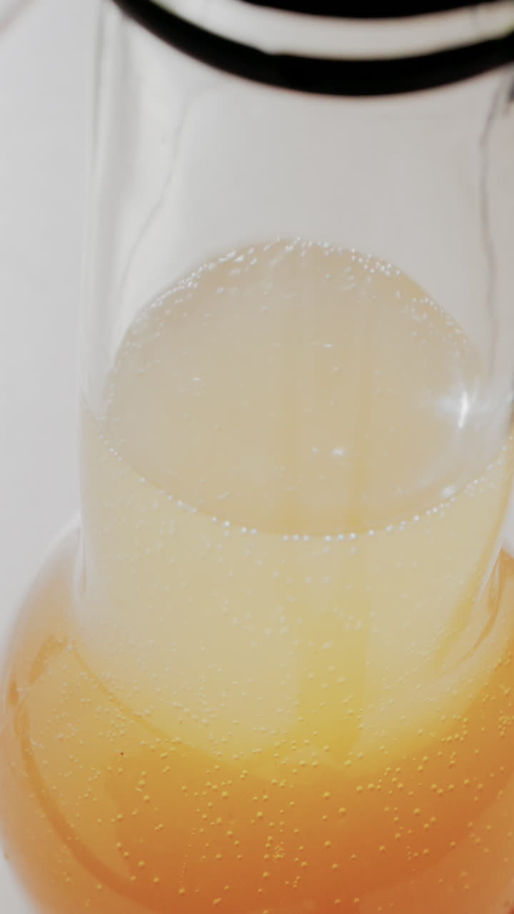 Primer plano de un refresco con burbujas doradas subiendo en un vaso. Vertical