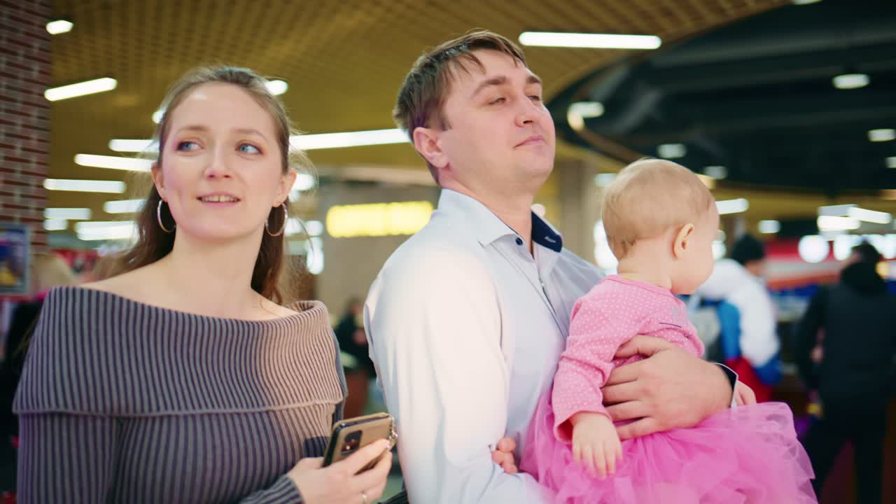 Young Family with Baby Girl Looking Around in a Shopping Mall