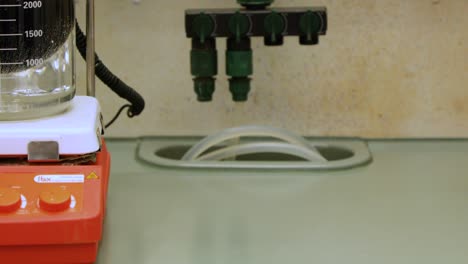 stirring chemical solution in a beaker submerged in ice for cooling in laboratory