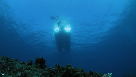 Looking-up-at-a-boat-with-swimmers-from-the-bottom-of-the-ocean