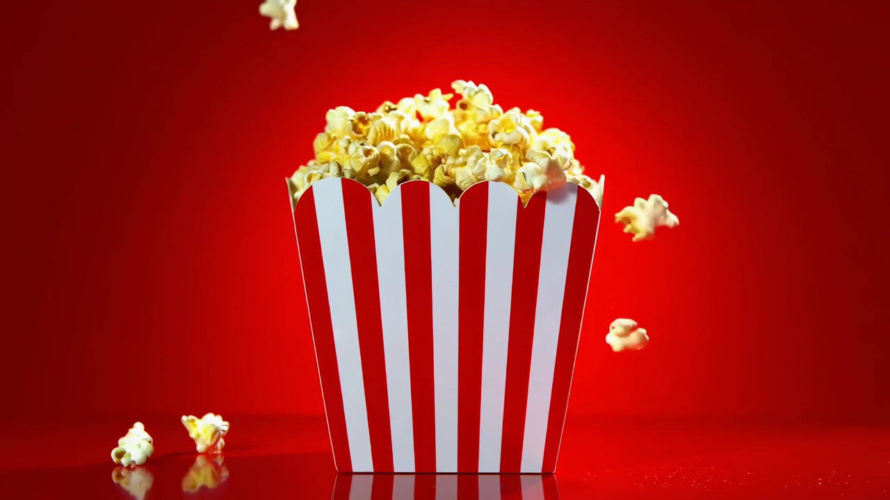 Popcorn che cadono in un classico secchiello a strisce su sfondo rosso