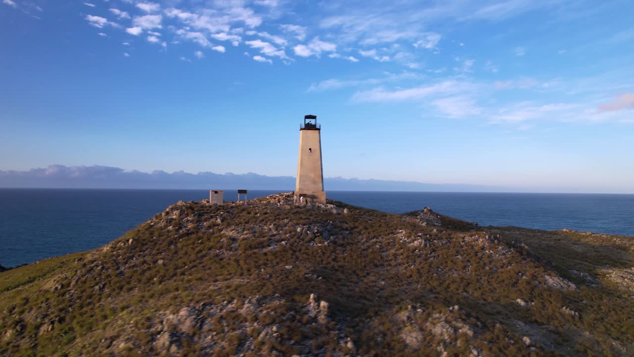 pueblo costero en venezuela con un faro, cielo despejado al anochecer, vista aérea