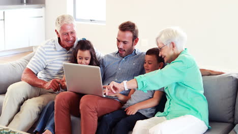 familia feliz de varias generaciones que usa una computadora portátil