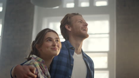 cheerful family smiling in new house. joyful man hugging woman after home repair