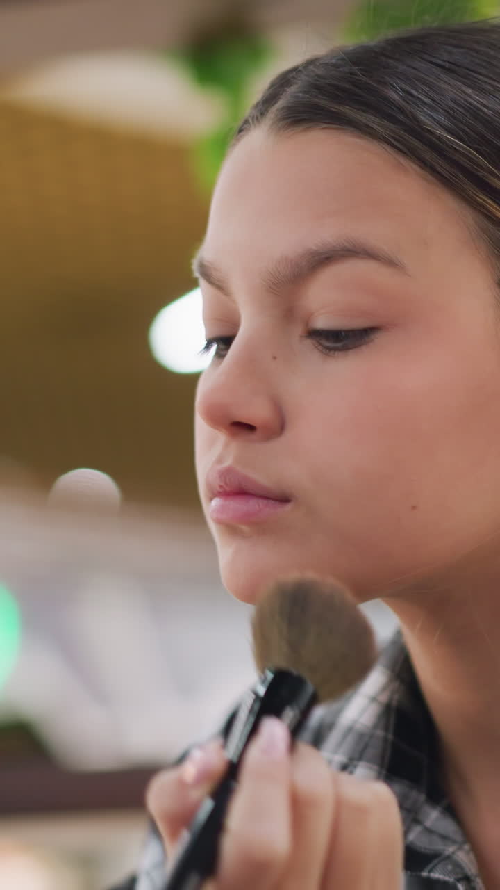 Teen model with makeup tools, Young female model practicing contouring techniques, Young female model under studio lights demonstrating makeup application and posing for editorial photography