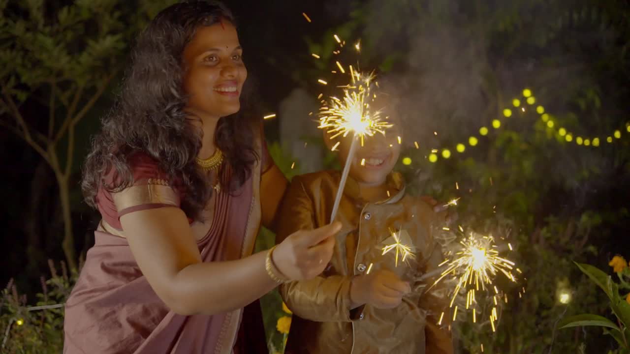 Diwali celebrating a Family Family Bursting Firecrackers in Diwali festival in india, mother and child enjoying with Firecrackers