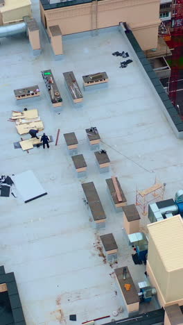 roof of multistorey building under construction. modern apartment house builds in the city. workers build the tower building. top aerial view. vertical video