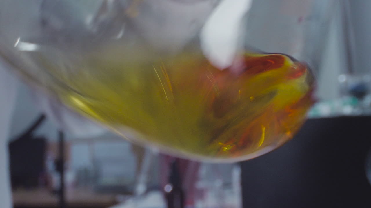 Close-up of a laboratory flask with a liquid substance swirling inside.