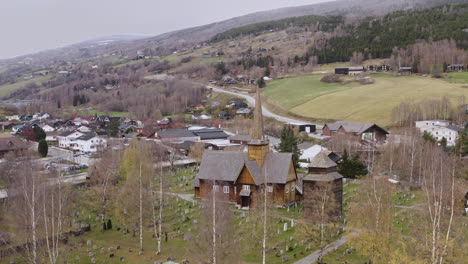 Wooden-Church-And-Cemetery-In-Vaga,-Norway---aerial-drone-shot