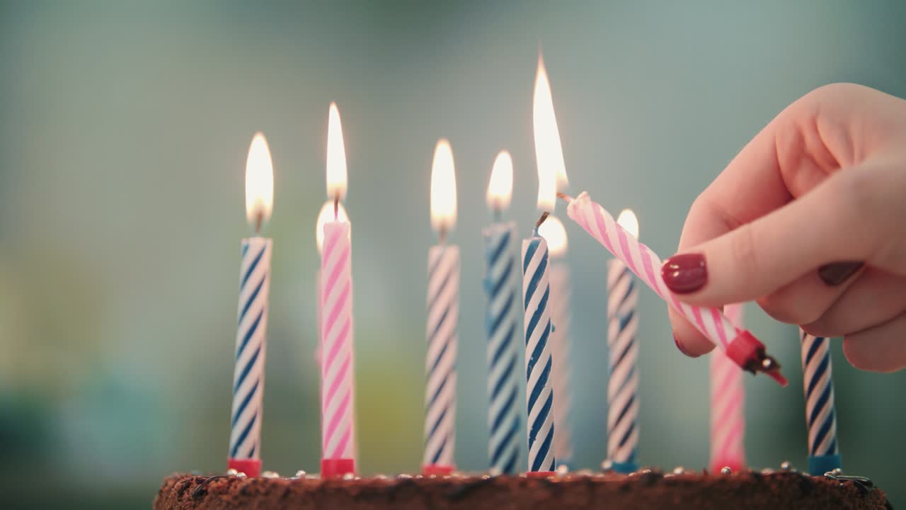 la mano de la mujer puso la llama de la vela en el pastel de cumpleaños. vela ardiente en el pastel de cumpleaños
