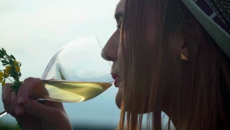Stunning-HD-footage-of-a-white-Caucasian-woman-with-a-knitted-hat-and-red-lipstick-stands-among-vineyards,-sipping-white-wine-from-a-glass-and-enjoying-the-view