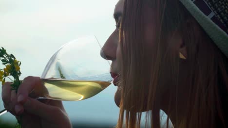 stunning hd footage of a white caucasian woman with a knitted hat and red lipstick stands among vineyards, sipping white wine from a glass and enjoying the view