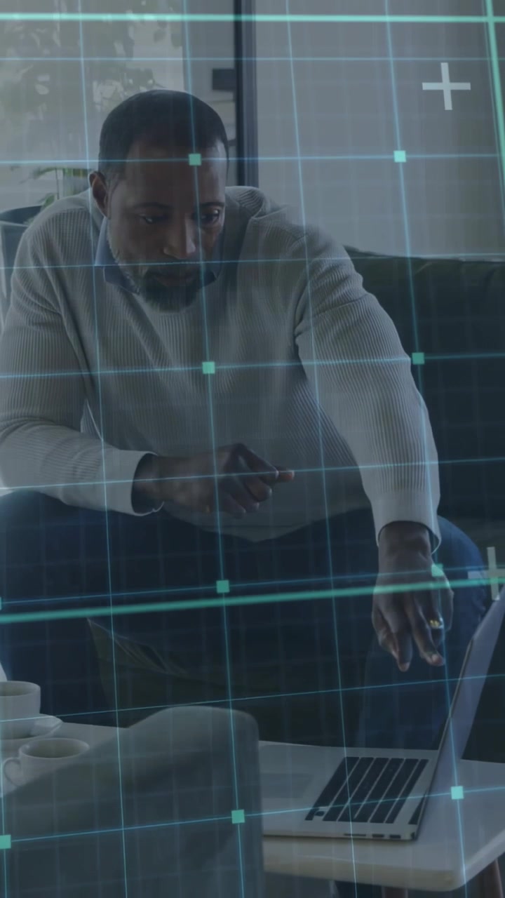 Vertical video: Man on sofa reaching trackpad with teal grid appearing, adjusting laptop for tech