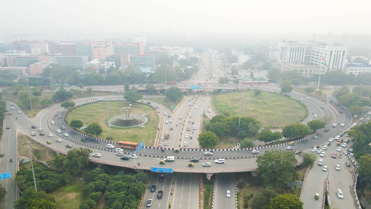 Aerial drone shot following the steady stream of traffic on a Delhi flyover, weaving through the city's dense infrastructure.