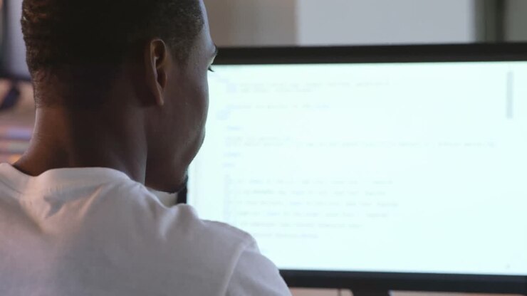 Rear view of black male executive working on computer at desk in office 4k