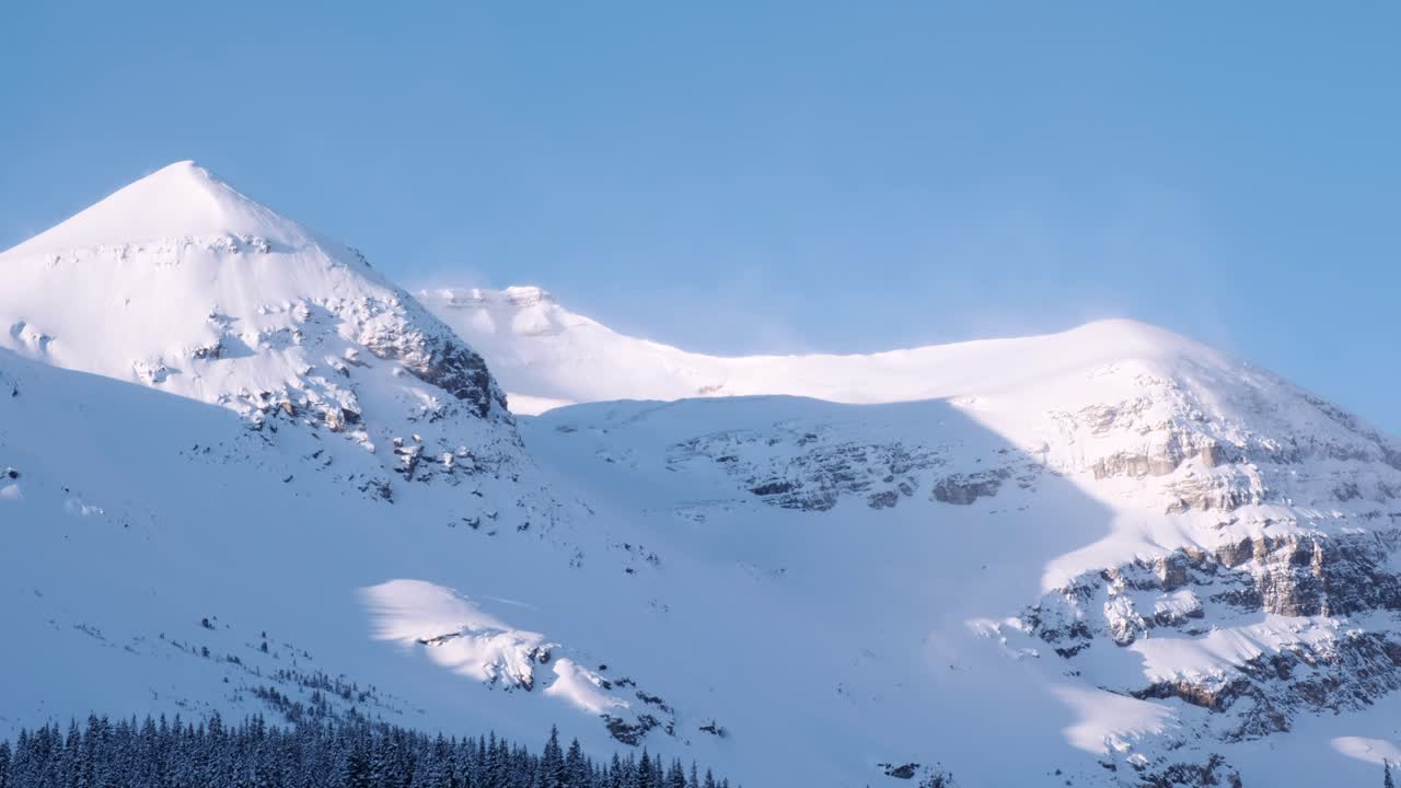 Snow blows around on Rocky Mountain peak on a cold, blue sky day