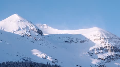 snow blows around on rocky mountain peak on a cold, blue sky day