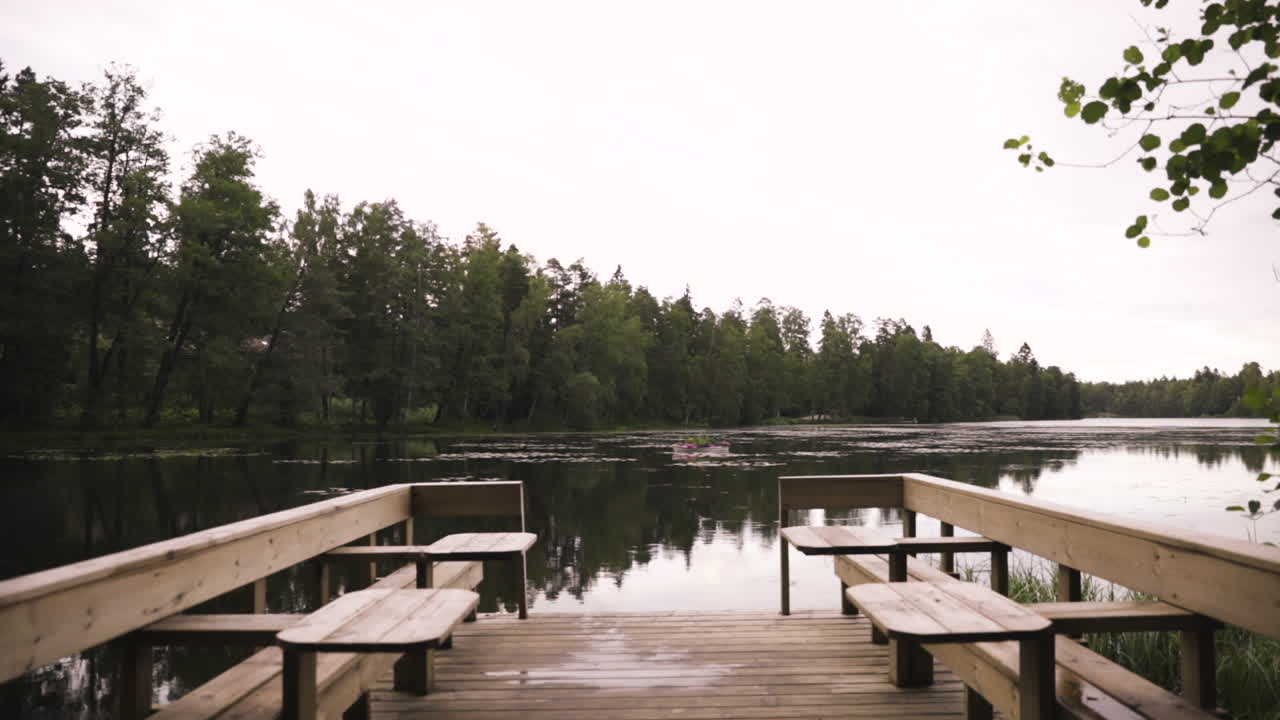 озеро у леса и деревянный мост со столиками в пасмурный день
