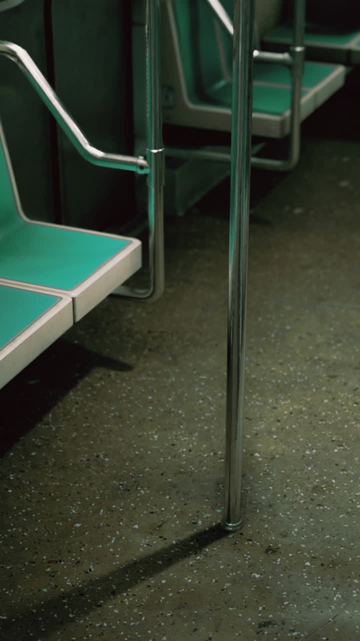 Innenraum einer leeren U-Bahn mit türkisfarbenen Sitzen und Metallstangen am Abend