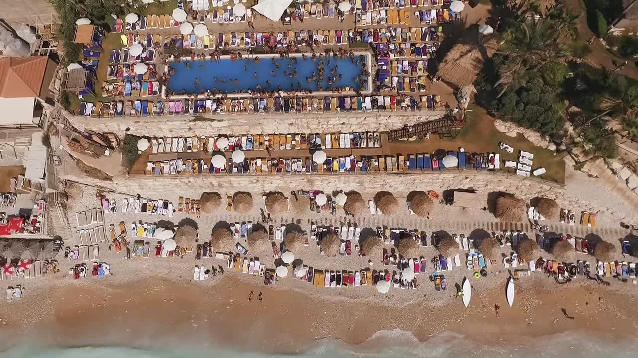 High aerial top down view of colorful seaside resort with many chairs and people