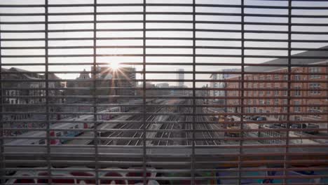 train passes by at sunset while looking through a steel industrial grid at the north-south connection in marolles, brussels