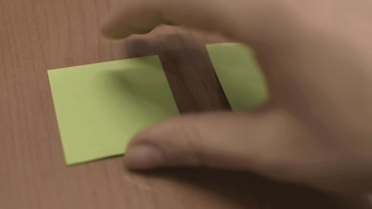 tomando una nota adhesiva verde y colocándola sobre la mesa, moviendo notas