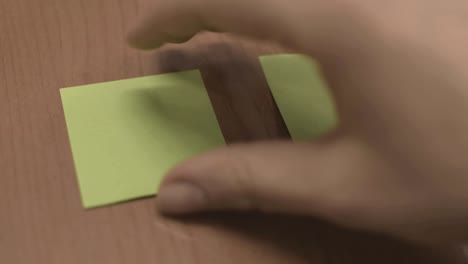 Taking-one-green-sticky-note-and-placing-it-on-table,-moving-notes