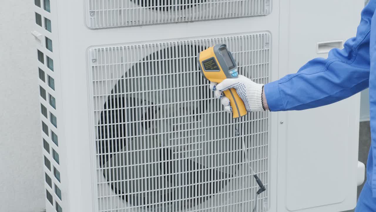Technician uses a thermal imaging infrared thermometer to check the condensing unit heat exchanger