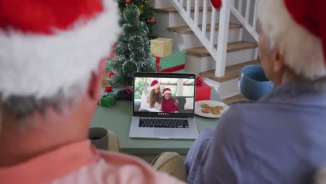 Happy-african-american-senior-couple-on-video-call-with-granddaughter-and-grandson-at-christmas