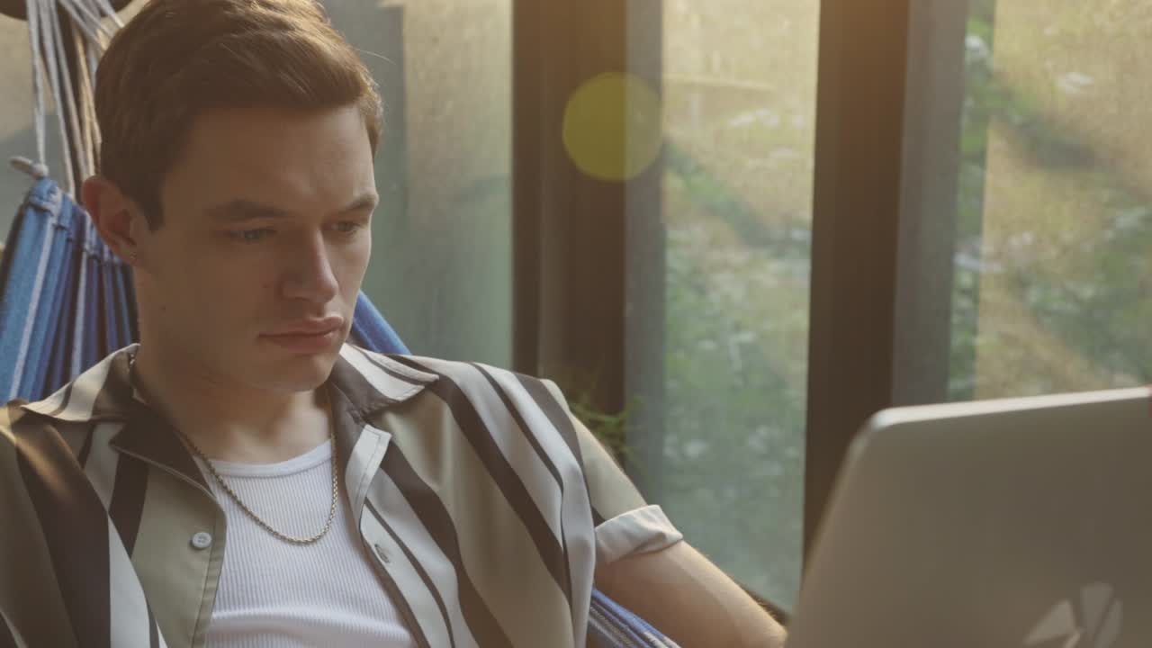 мужчина использует свой ноутбук во время отдыха в гамаке - близко