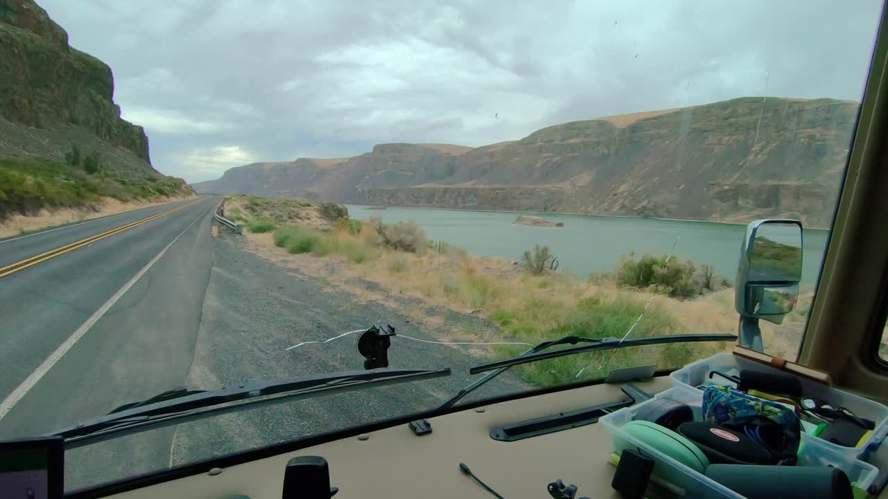 Punto di vista del conducente di un camper di Classe A parcheggiato, vista del Lago Lenore e dell'Autostrada 17 nello Stato di Washington in una giornata nuvolosa e ventosa.